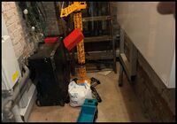 Das Bild zeigt einen großen Spielzeugkran, an dem eine rote Box hängt. Daneben steht ein Spielzeug Kipplader, in den man die Box ablegen musste.